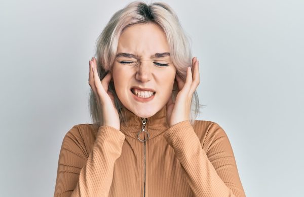 Young blonde girl wearing casual clothes covering ears with fingers with annoyed expression for the noise of loud music. deaf concept. Young blonde girl wearing casual clothes covering ears with fingers with annoyed expression for the noise of loud music. deaf concept.